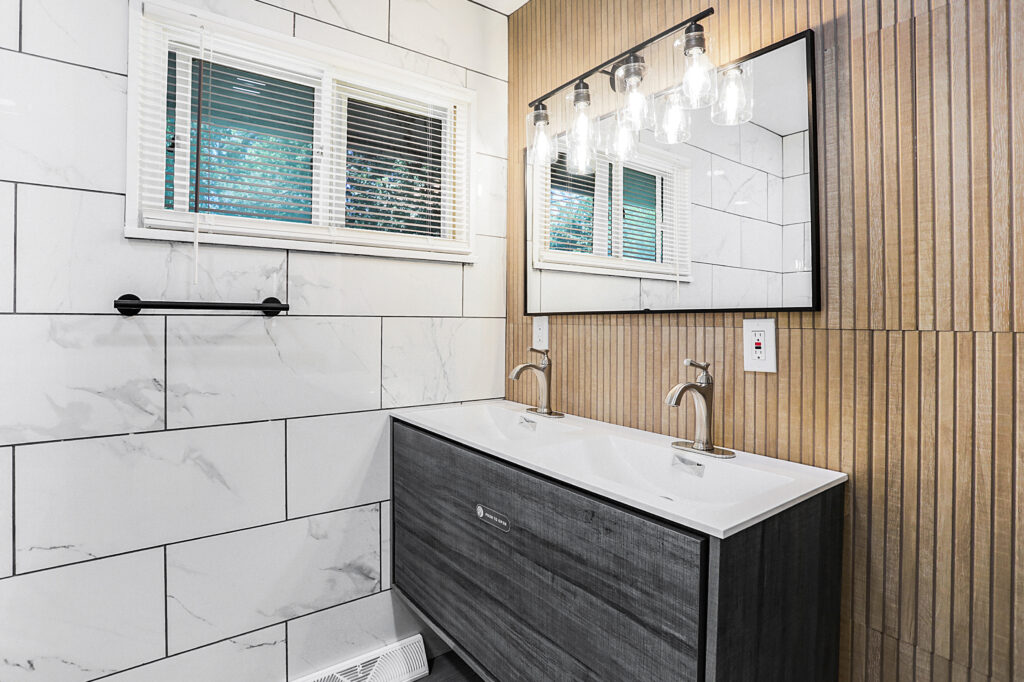 Modern double vanity bathroom renovation with marble tile walls by Elot LLC in Indianapolis